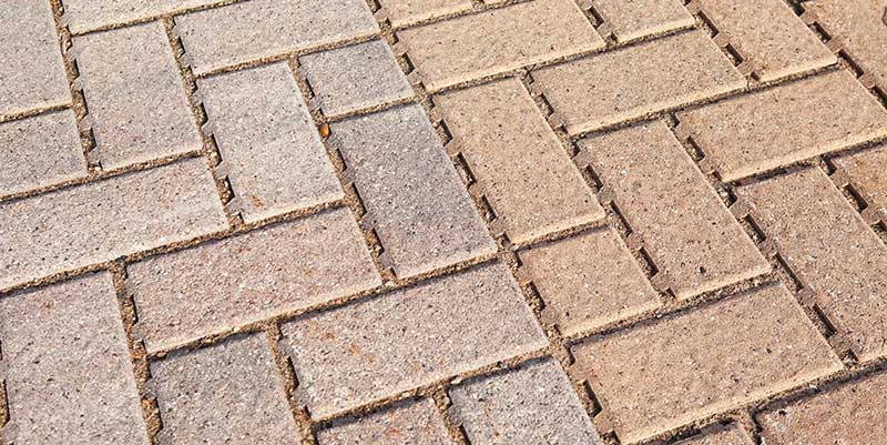 A close-up of gray and pink pervious pavers set in sand