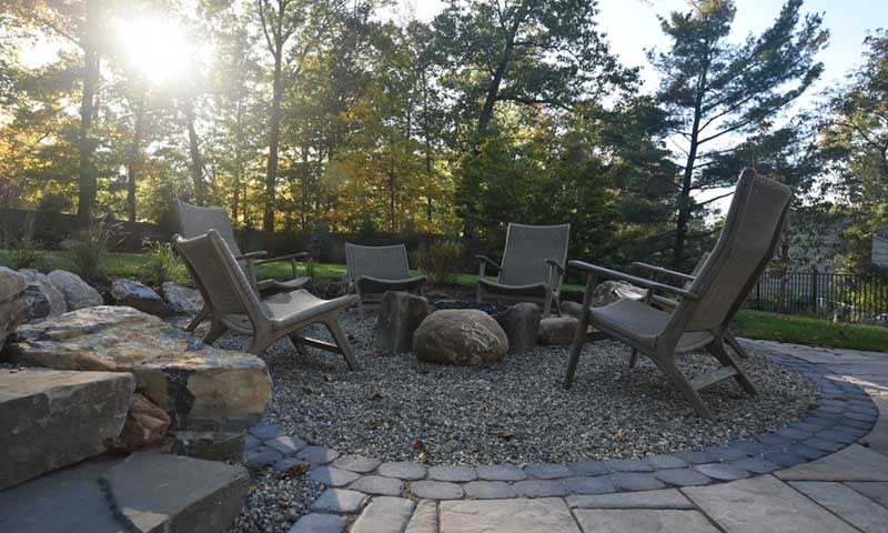 Five chairs surround a firepit of stone and boulders