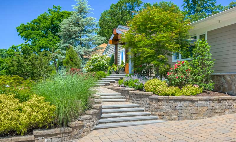 Colorful trees and shrubs line walkway and steps to front of home