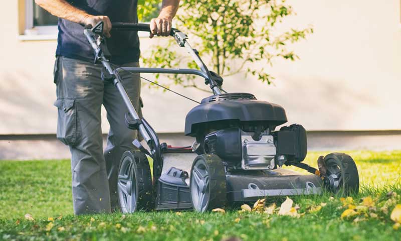 Man mowing a lawn in early fall