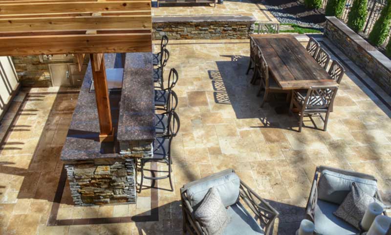 A drone view of a backyard patio with a bar, dining, and seating areas