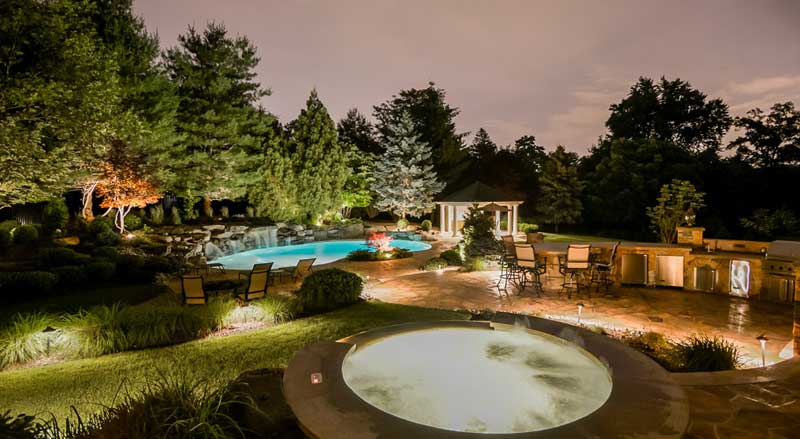 A beautiful professionally landscaped back yard with pool, jacuzzi, and outdoor kitchen