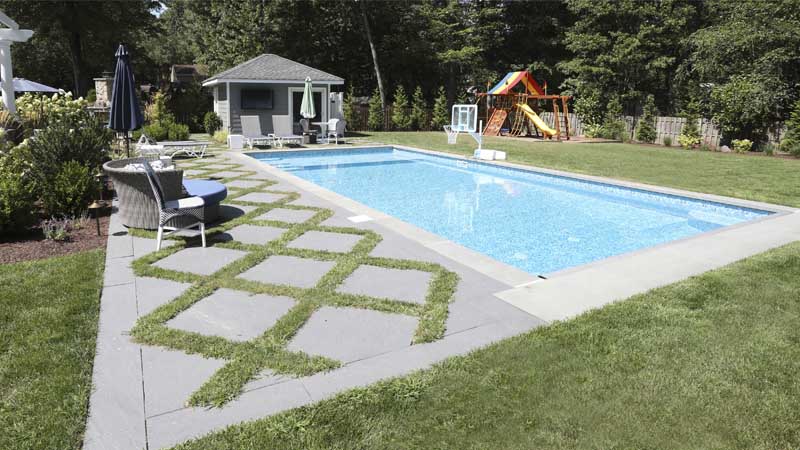 A pool and patio area featuring a paver patio with grass joints
