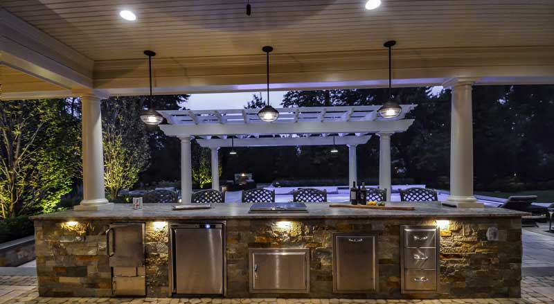 A pavilion with an outdoor kitchen and a pergola nearby