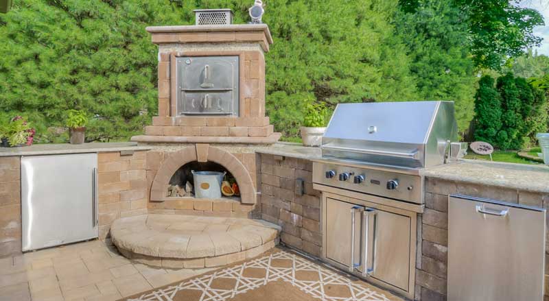 An outdoor kitchen and pizza oven with patio and stonework