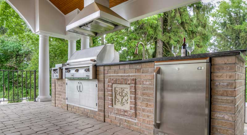 An outdoor kitchen on a stone paver patio