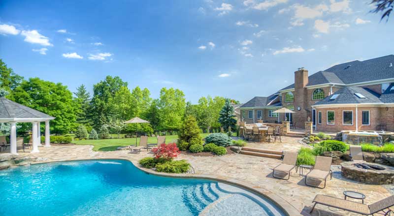 A swimming pool and expansive pool deck with gazebo and landscaping