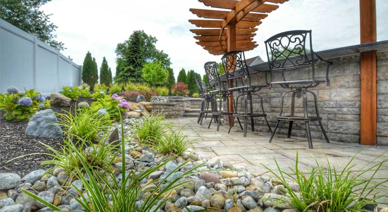 A patio area with a rock garden with ornamental grasses