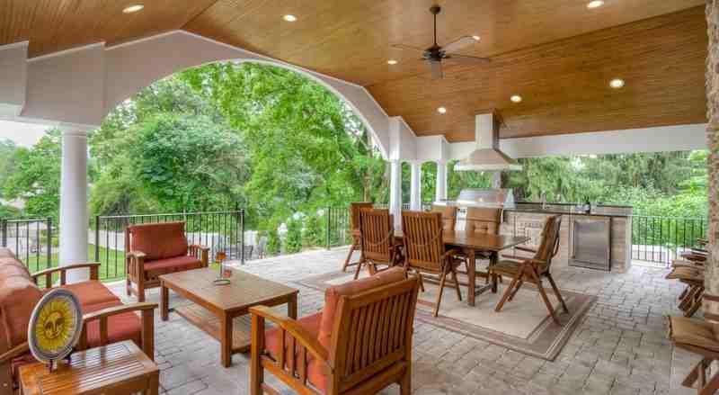 A large patio that features an outdoor kitchen with an ample amount of seating for guests