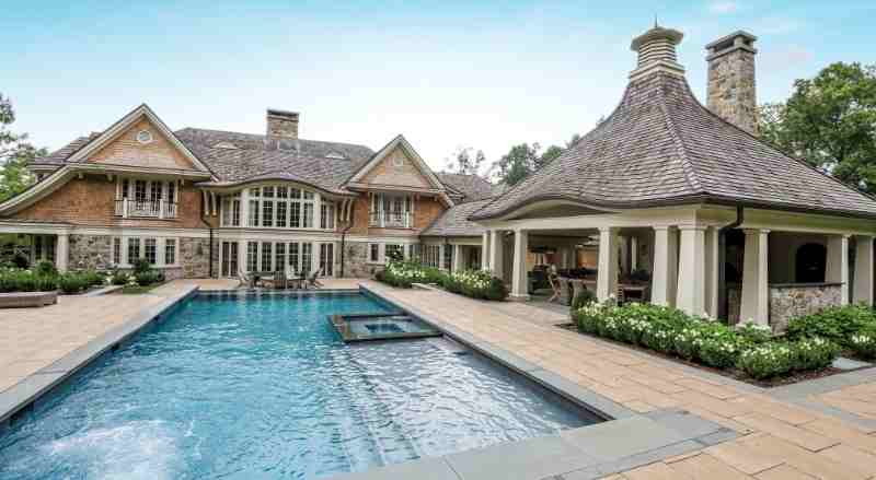 Large, luxurious backyard with a swimming pool, spa, and a covered patio area attached to a two-story home