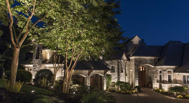 night shot of front exterior home with luxury landscape lighting