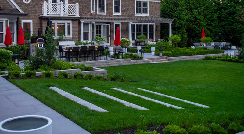 Modern backyard landscaping with tiered garden beds, vibrant greenery, and an outdoor dining area