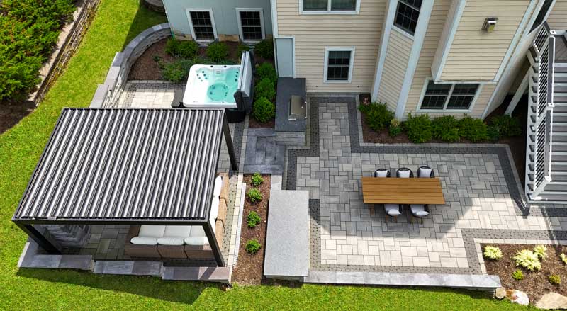 Aerial view of modern backyard patio with pergola, dining space, and hot tub for year-round outdoor living
