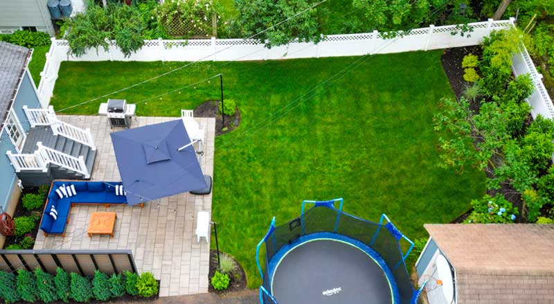 Spacious backyard with patio seating, trampoline, and well-maintained lawn for seasonal enjoyment
