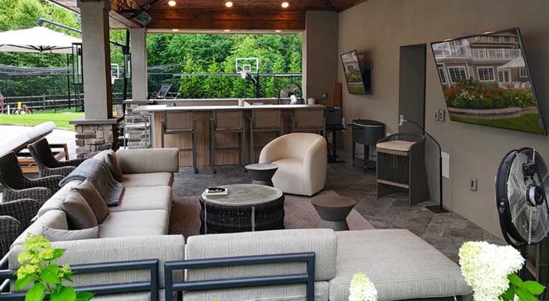 Contemporary pavilion featuring a full outdoor bar, cushioned seating, and mounted TVs—perfect for relaxing and entertaining.