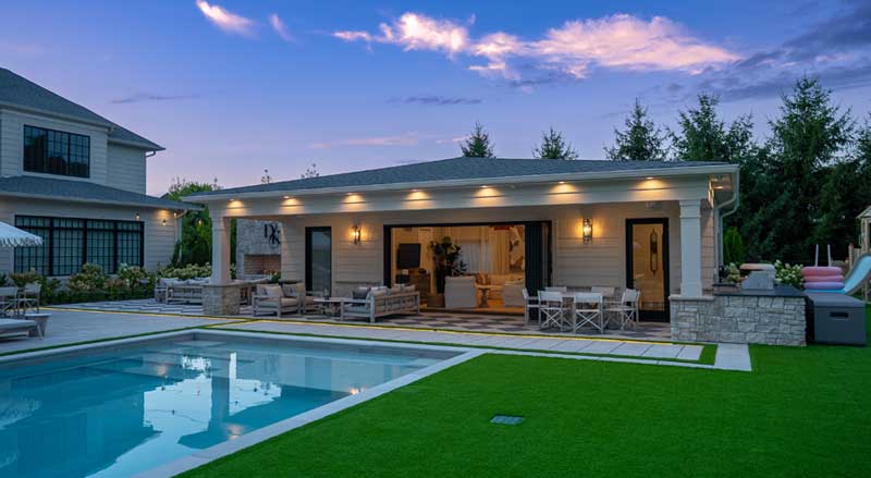 Luxury poolside pavilion with outdoor seating and ambient lighting at sunset, expanding the home’s living space into the backyard