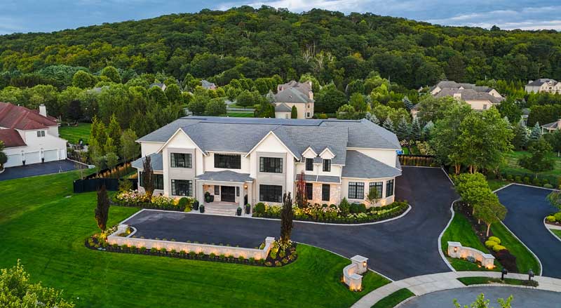 Large luxury New Jersey home with a pristine lawn, landscaped beds, and driveway lighting that enhances fall curb appeal