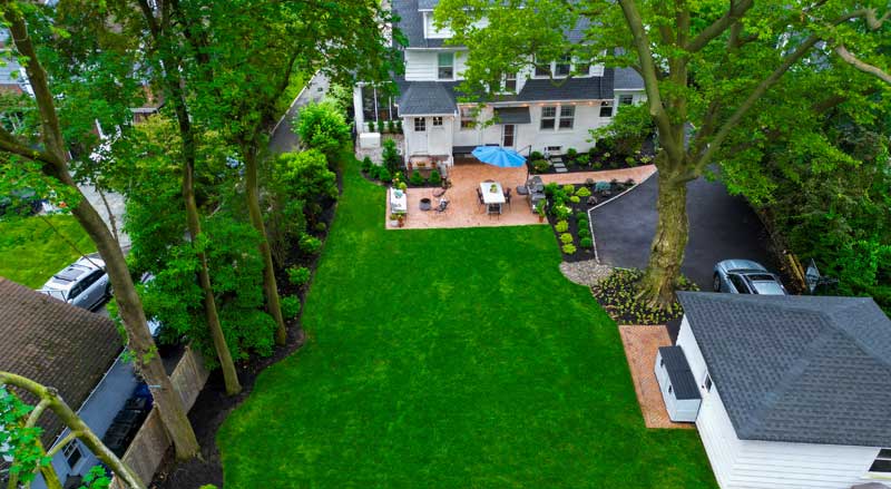 Expansive residential backyard with green lawn and patio seating, ideal for seasonal planting and outdoor entertaining