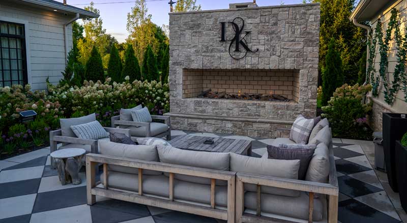 Custom outdoor fireplace surrounded by cozy lounge seating, adding luxury and resale value to New Jersey home