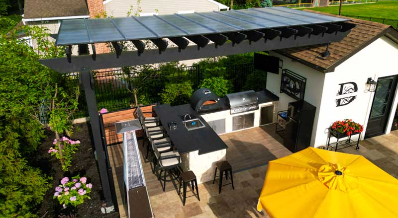 High-end outdoor kitchen with pergola, grill, and bar seating designed for entertaining