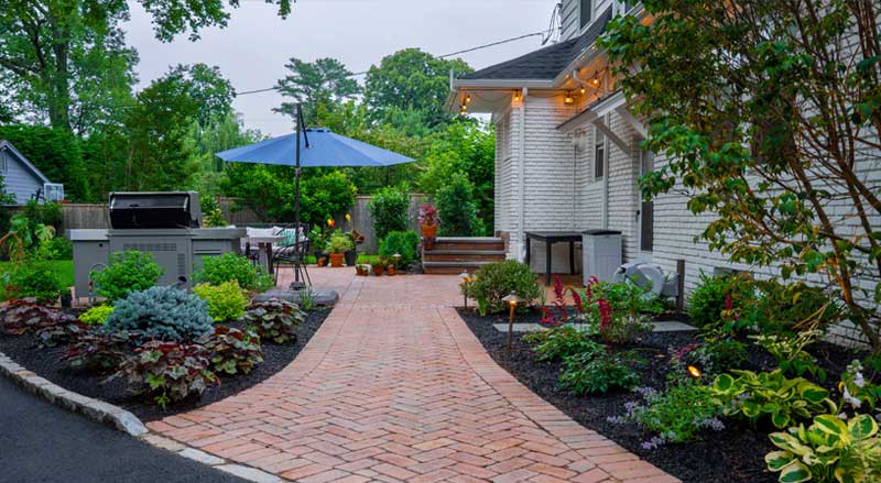 Eco-friendly brick patio surrounded by native plants, efficient irrigation, and LED lighting