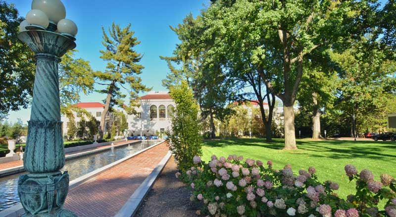 HOA green space with brick walkway, water feature, and mature shade trees