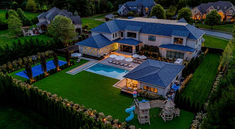 Luxury backyard at dusk with pool, pavilion, sports court, and outdoor living spaces designed through a landscape master plan