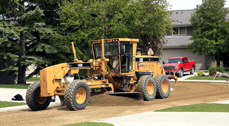 Heavy equipment performing site grading to prepare land for drainage and landscape installation