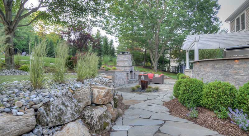 Natural stone patio with integrated grading and drainage to manage water flow in outdoor living space