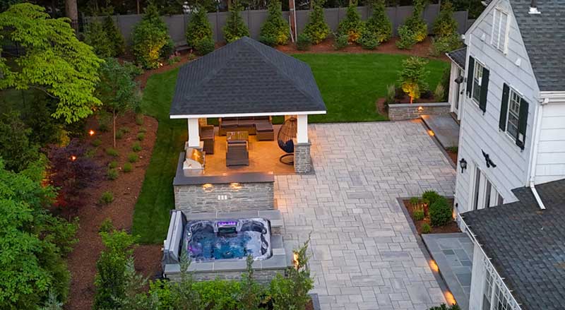 Covered outdoor pavilion with lounge seating, integrated spa, and spacious patio creating a dedicated outdoor living room environment