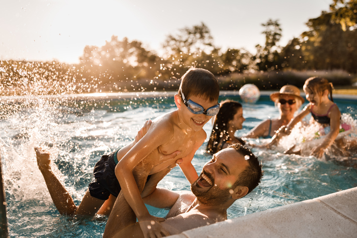 Family enjoying an inground swimming pool as part of a backyard outdoor living space