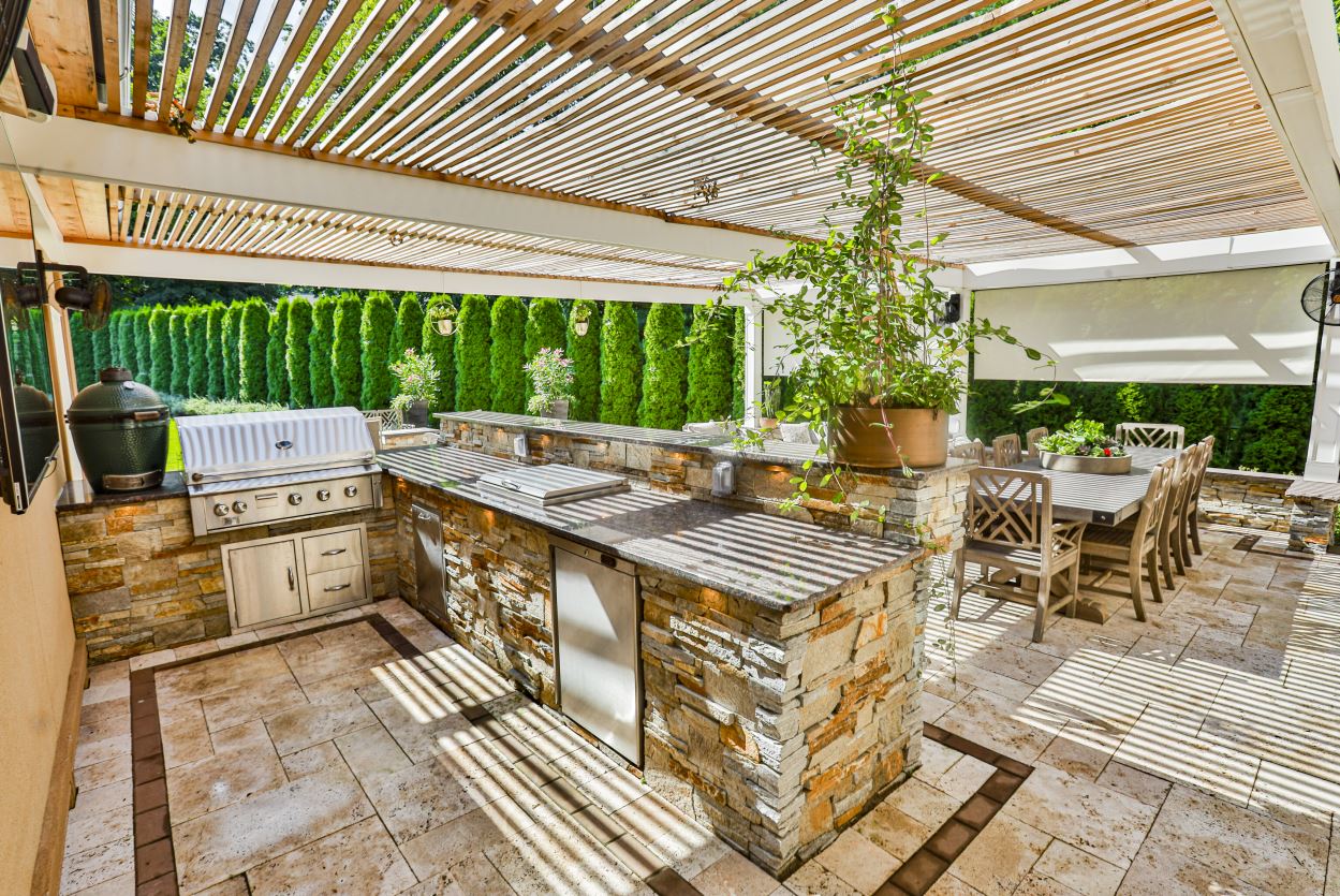 Outdoor kitchen and dining area under a wood pergola