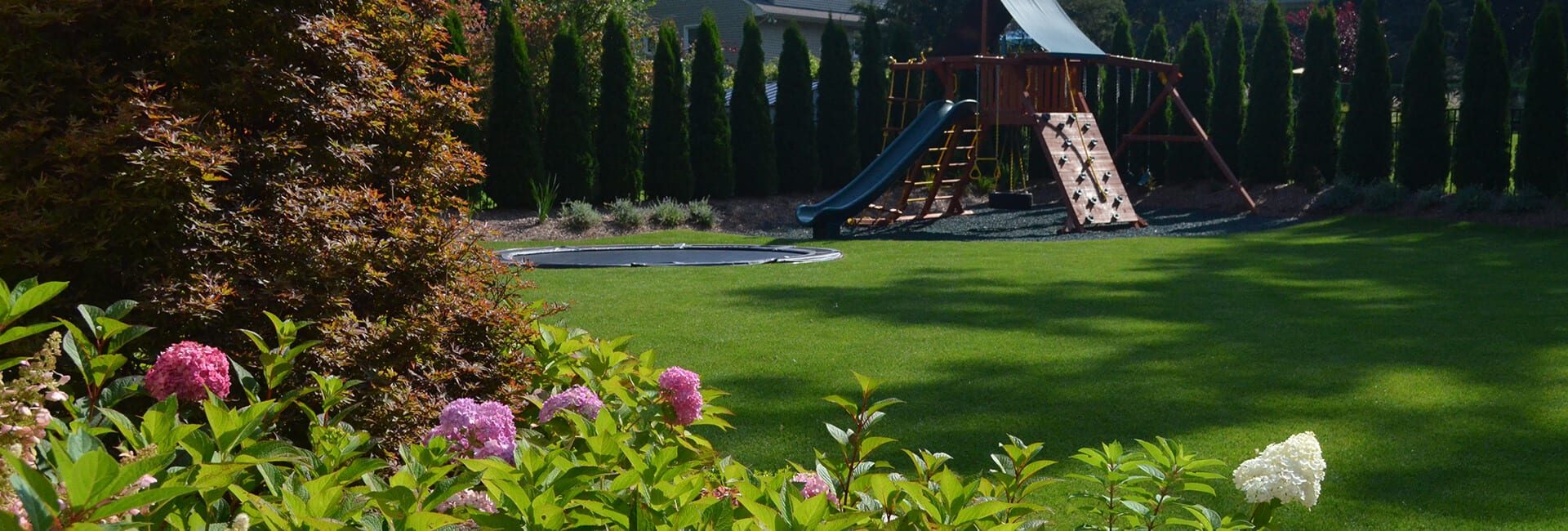 Organic Lawn Care – Sponzilli Landscape Group Beautiful Lawn - Backyard with Garden. Privacy Fence and Play Area