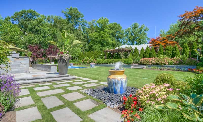 Backyard path with fountain and colorful pink, red, and purple plants, plant-along-high-traffic-areas